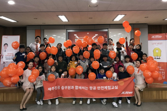 제주항공이 지난 6일 광주 상무초등학교에서 진행한 '항공안전체험교실'에 참가한 객실승무원과 어린이들이 기념촬영을 하고 있는 모습.<제주항공 제공>